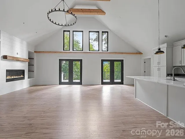 a view of an empty room with window and wooden floor
