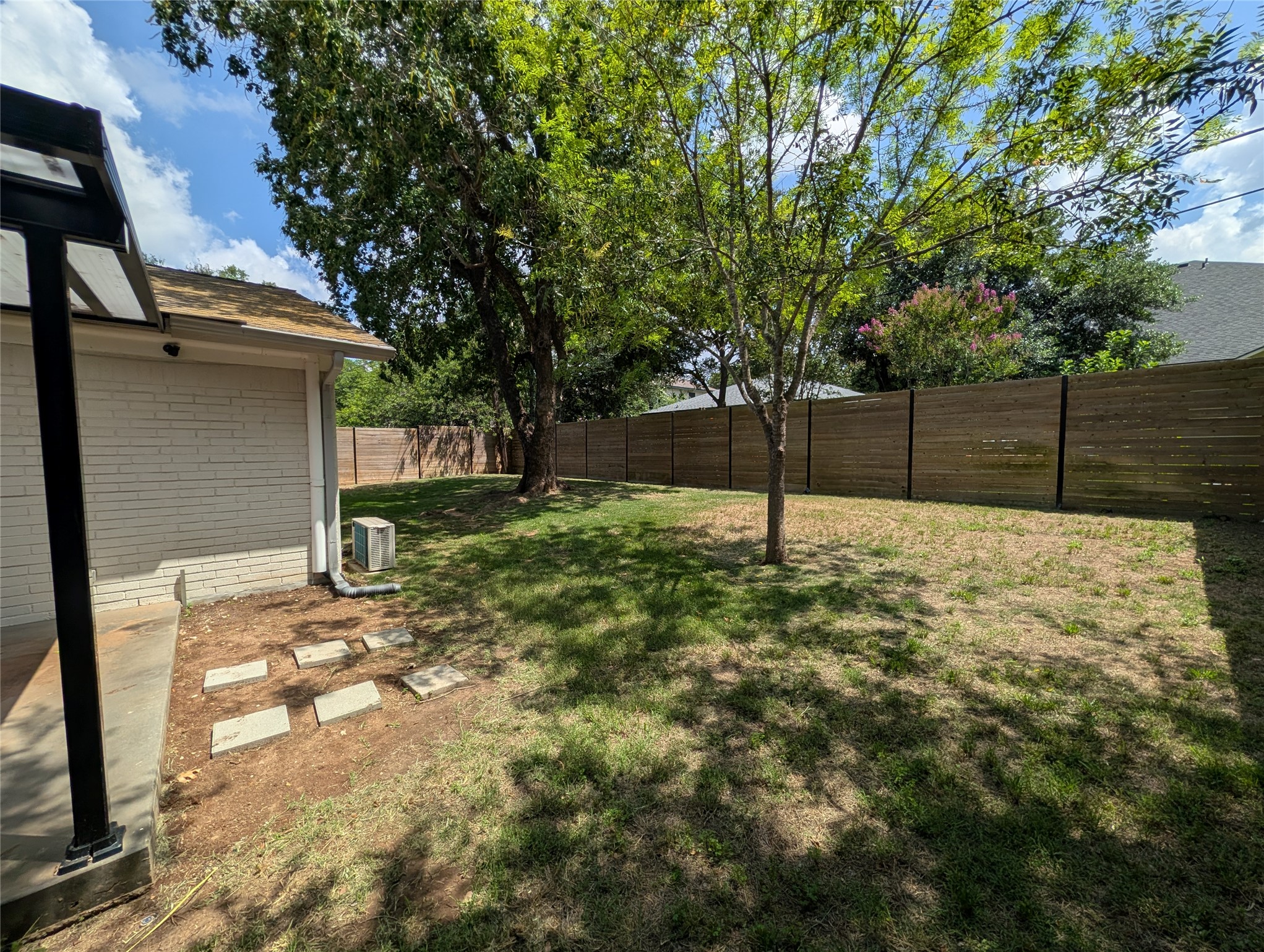 4601 Tamarack Trail Austin, TX 78727 - Photo 7 of 19 A secluded backyard features a wooden fence, mature trees, and a well-maintained lawn, offering privacy.