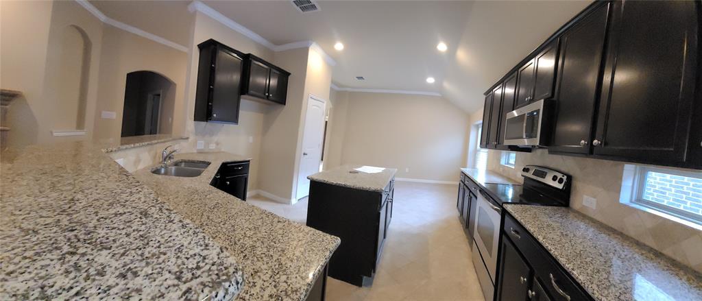 11821 Beach Street Frisco, TX 75036 - Photo 22 of 38 Kitchen with appliances with stainless steel finishes, light stone countertops, ornamental molding, recessed lighting, and dark cabinetry