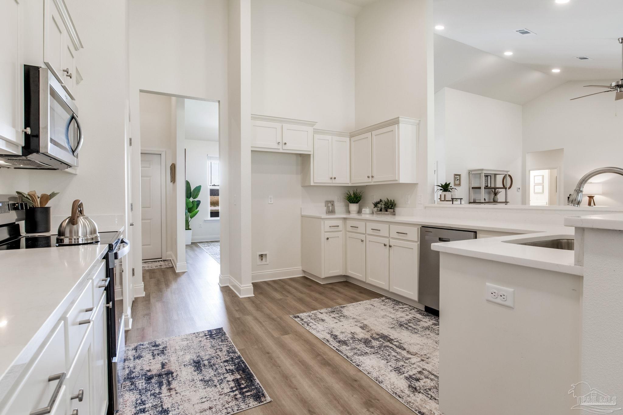 4404 Russell Elliott Road Jay, FL 32565 - Photo 15 of 62 a kitchen with a sink dishwasher stove and white cabinets with wooden floor