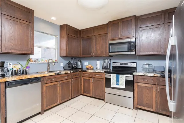 a kitchen with stainless steel appliances granite countertop wooden cabinets a sink a stove a microwave and island