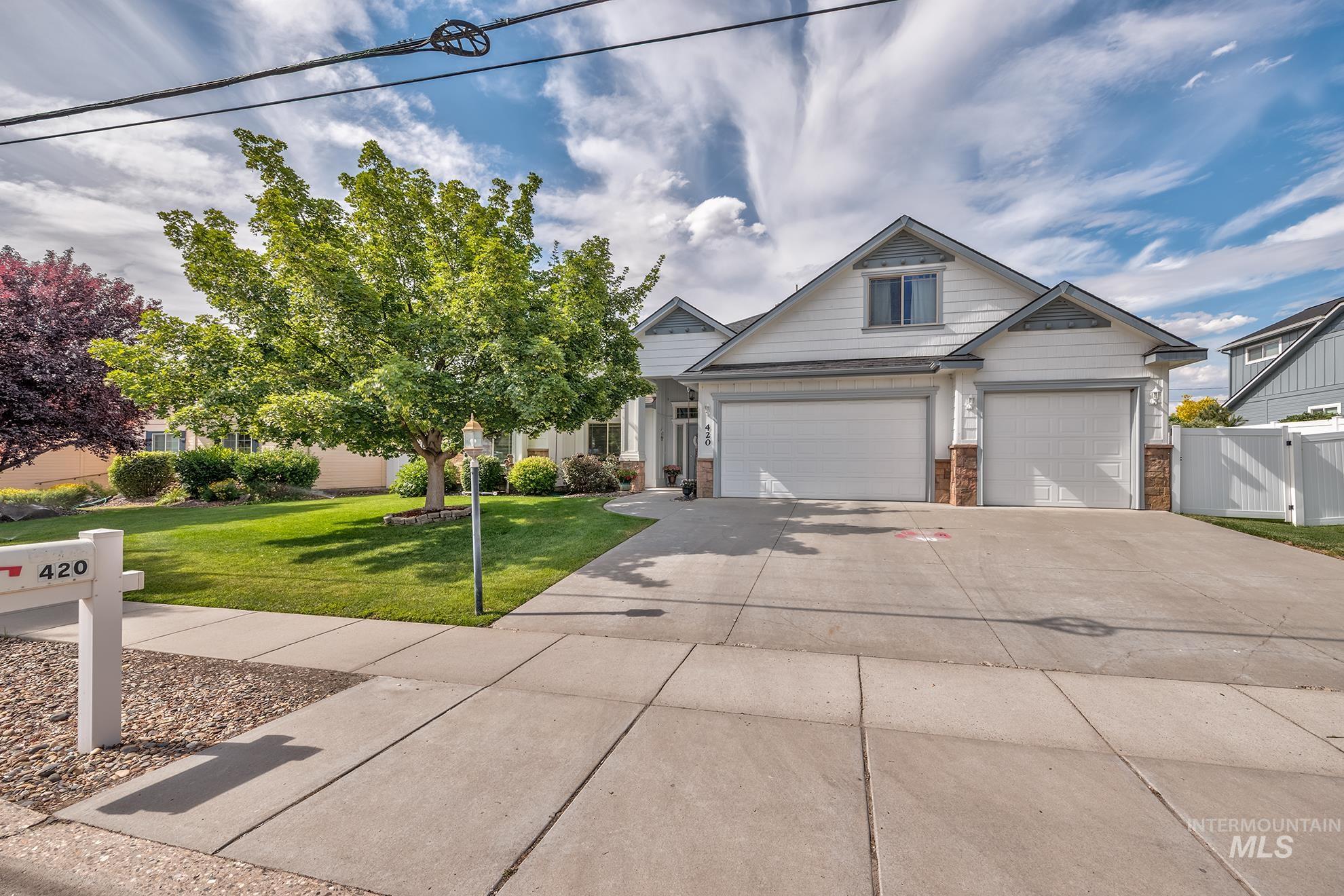420 West Indianhead Road Weiser, ID 83672 - Photo 39 of 40 White siding exterior with a two-car garage, contrasting brick accents, a mature front yard tree, and a concrete driveway