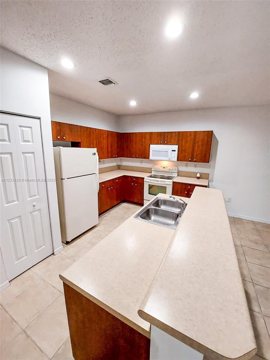 4282 Northeast 9th Street, Unit 4282 Homestead, FL 33033 - Photo 8 of 28 a large white kitchen with sink a refrigerator and a stove