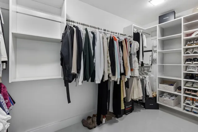a view of walk in closet with clothes and shoes
