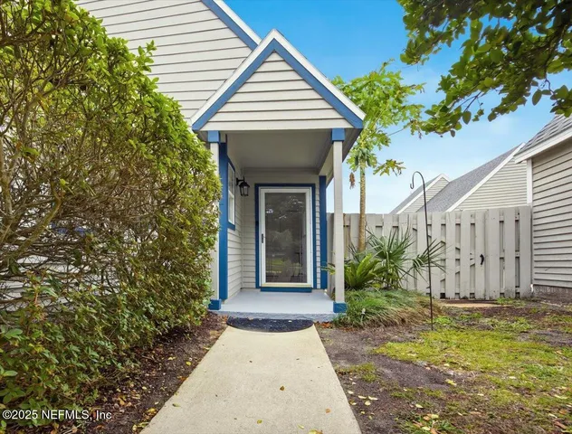 a view of a house with potted plants and a large tree