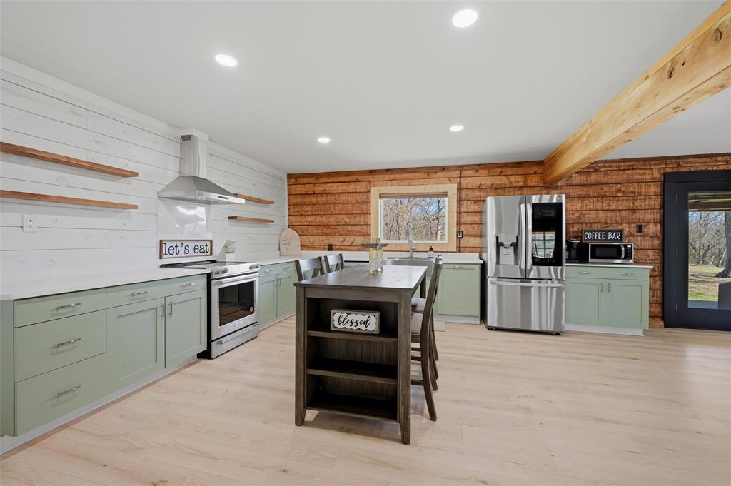 230 Frosty Hollow Road Denison, TX 75021 - Photo 12 of 40 a kitchen with stainless steel appliances kitchen island granite countertop a stove top oven a sink dishwasher a dining table and chairs with wooden floor