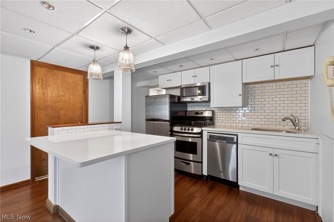 5346 Burlawn Street Northwest Canton, OH 44708 - Photo 29 of 40 Kitchen featuring stainless steel appliances, white cabinetry, subway tile backsplash, and wood-finish flooring