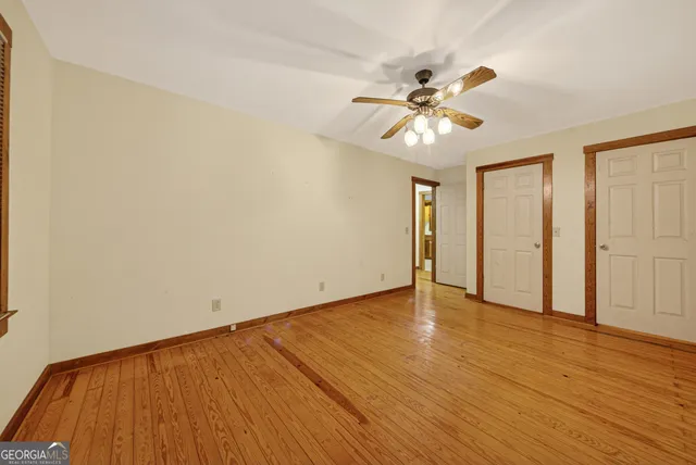 a view of an empty room with window and wooden floor