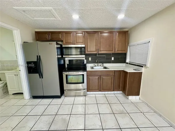 a kitchen with stainless steel appliances a refrigerator sink and microwave