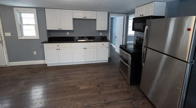a kitchen with granite countertop a refrigerator and a stove top oven