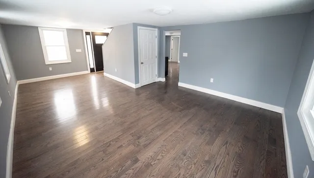 a view of an empty room with wooden floor and window