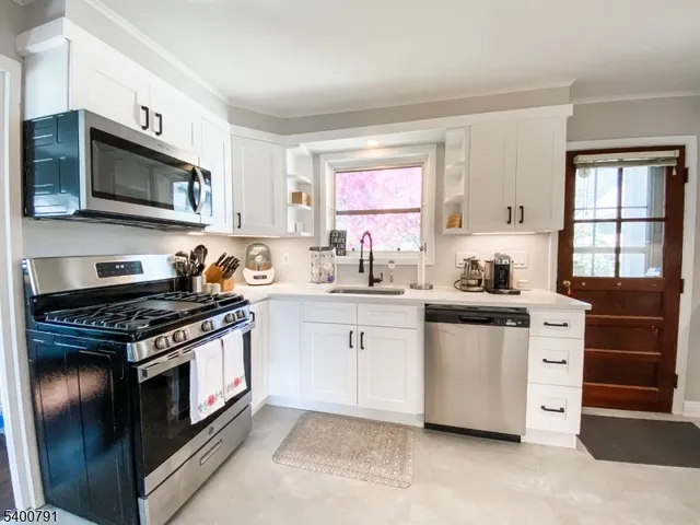 a kitchen with stainless steel appliances granite countertop a stove a sink and a microwave
