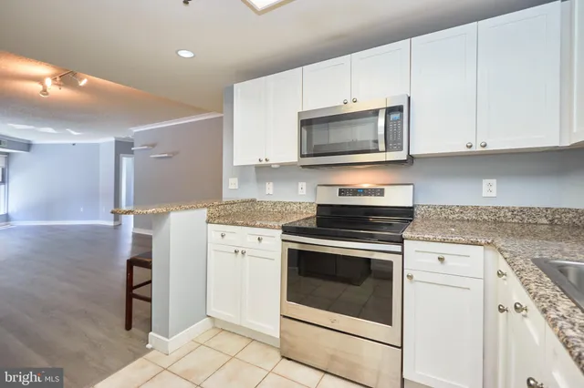 a kitchen with cabinets stainless steel appliances and wooden floor