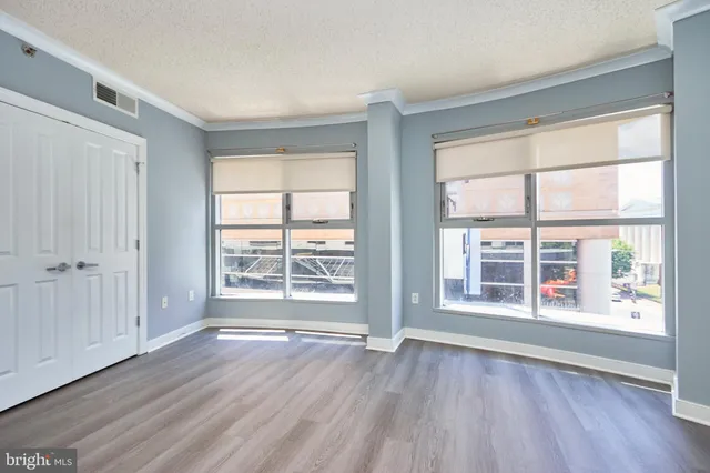 an empty room with wooden floor and windows