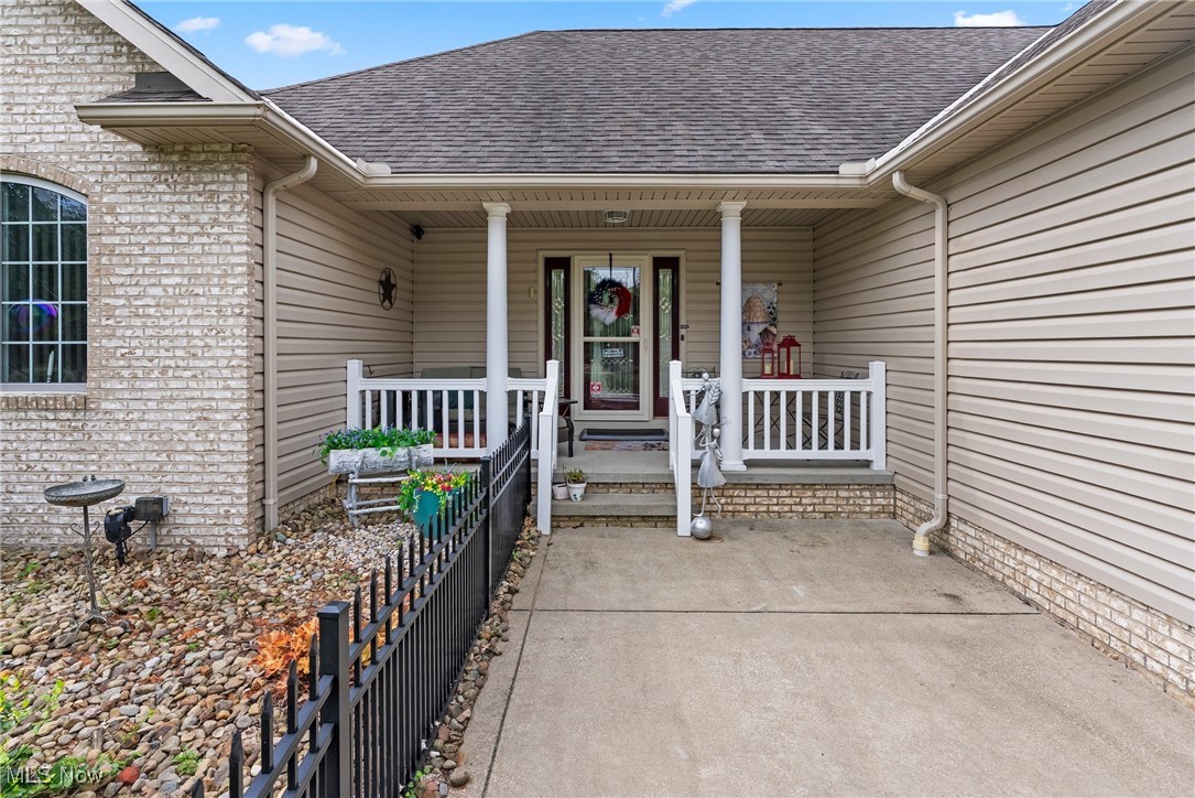 6810 South Ridge Road West Geneva, OH 44041 - Photo 2 of 41 Doorway to property with a shingled roof, covered porch, and brick siding