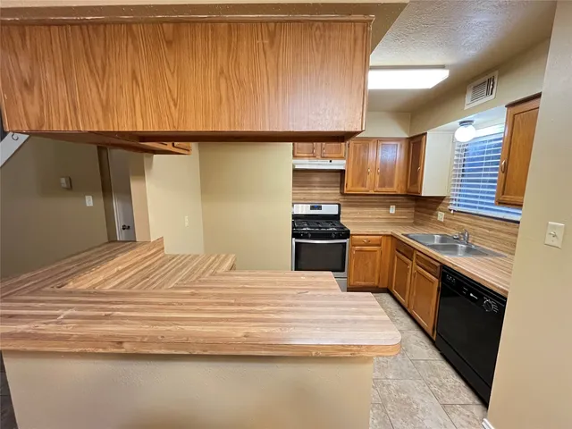 a kitchen with granite countertop wooden cabinets and stainless steel appliances