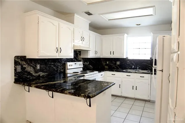 a kitchen with stainless steel appliances a stove a refrigerator a sink and white cabinets