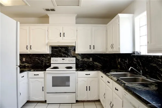 a kitchen with granite countertop white cabinets and white appliances
