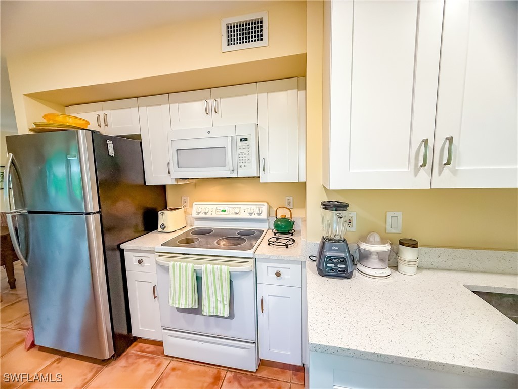 4511 Conch Shell Drive Upper Captiva, FL 33924 - Photo 9 of 50 a kitchen with a stove a refrigerator and cabinets