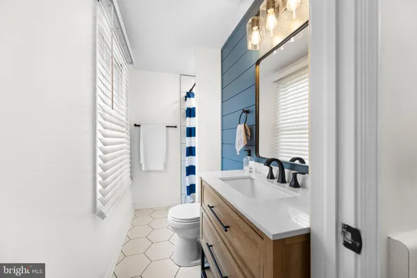 a bathroom with a sink a toilet a mirror and shower