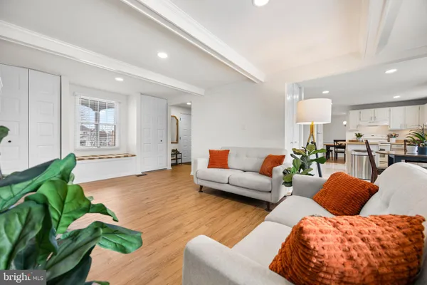 a living room with furniture a rug kitchen view and a window