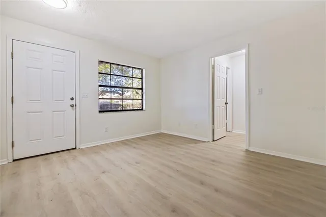 an empty room with wooden floor closet and windows