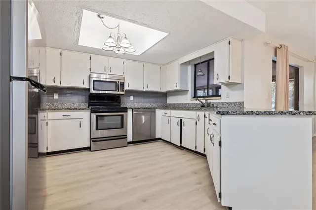 a kitchen with granite countertop a sink stainless steel appliances and white cabinets