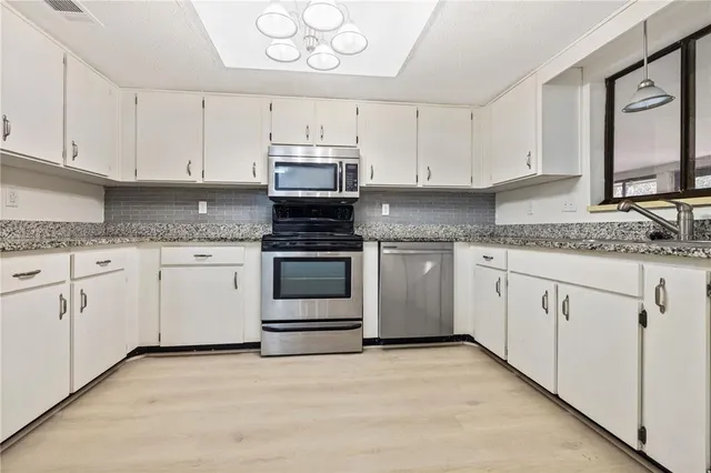 a kitchen with granite countertop white cabinets and white appliances