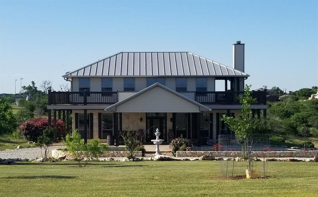 7060 Hells Gate Loop Strawn, TX 76475 - Photo 1 of 40 Rear view of property featuring a standing seam roof, a lawn, and a chimney