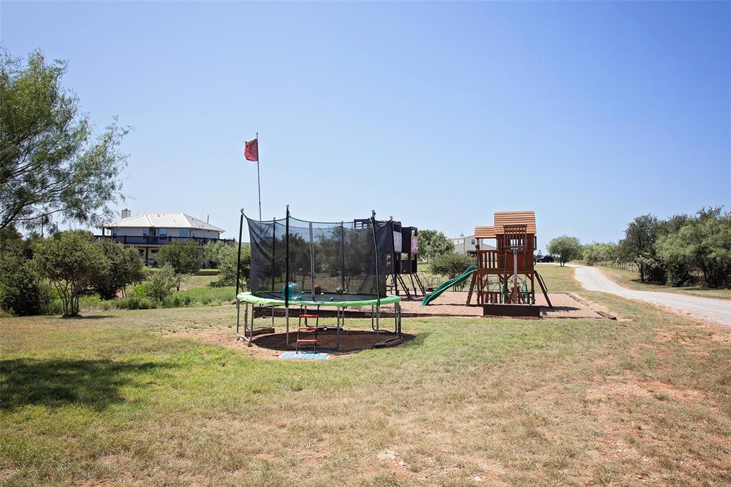 7060 Hells Gate Loop Strawn, TX 76475 - Photo 24 of 40 Private play area with a trampoline and a yard