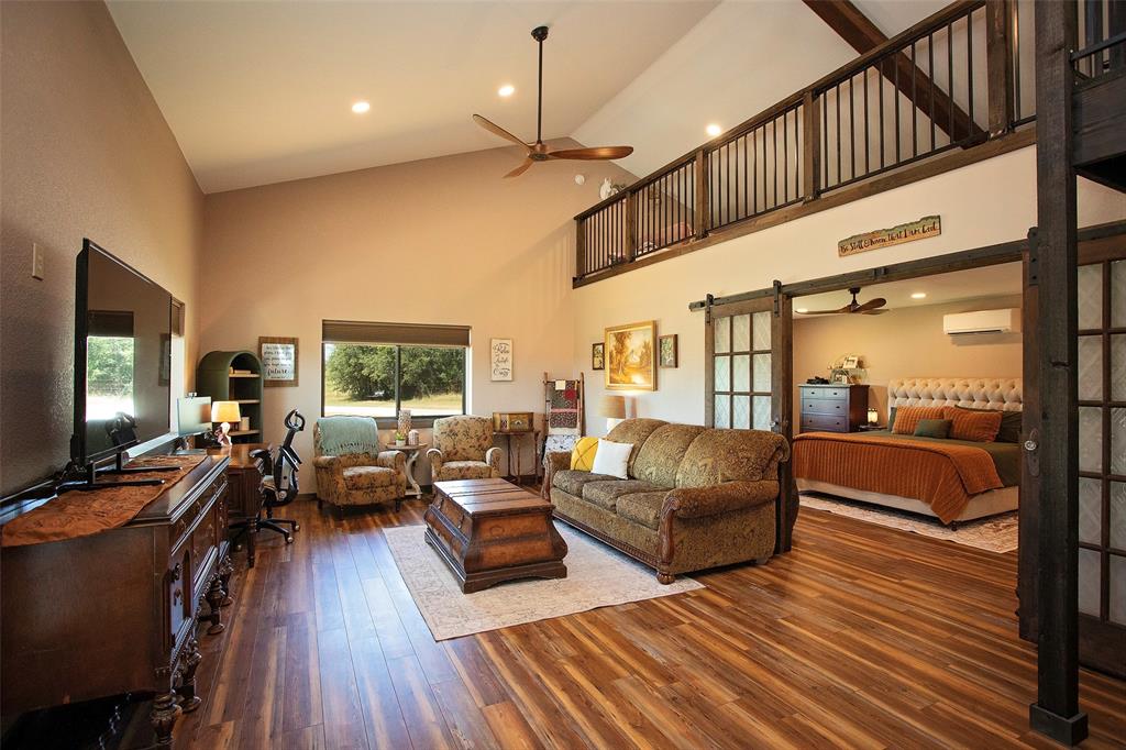 7060 Hells Gate Loop Strawn, TX 76475 - Photo 34 of 40 Living area featuring high vaulted ceiling, ceiling fan, hardwood / wood-style floors, a wall mounted air conditioner, and a barn door