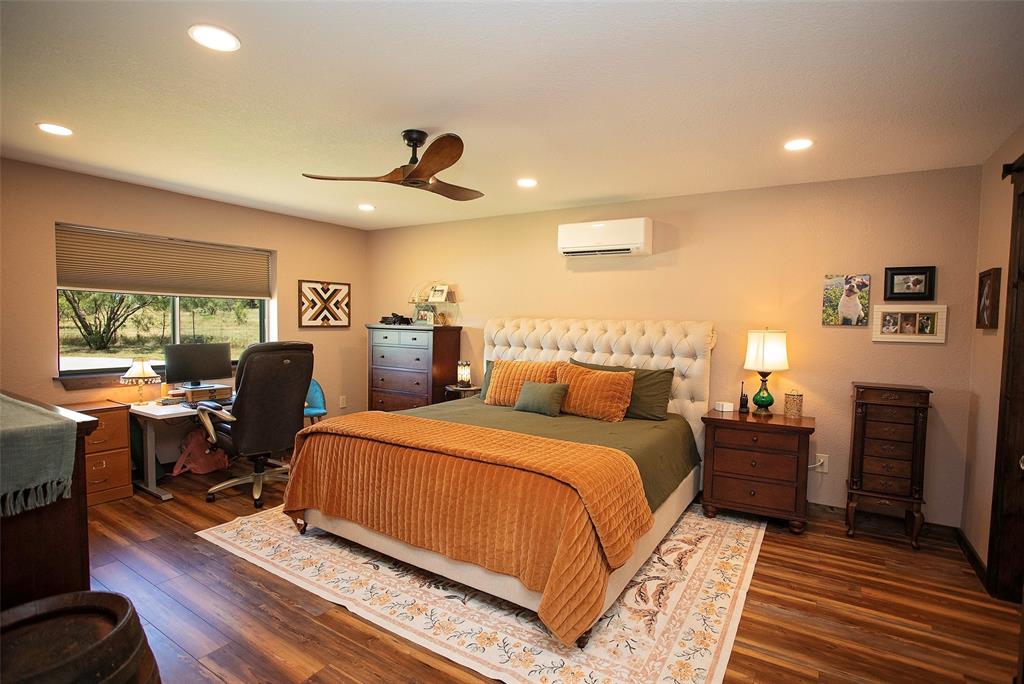 7060 Hells Gate Loop Strawn, TX 76475 - Photo 36 of 40 Bedroom featuring a wall unit AC, wood finished floors, an office area, a ceiling fan, and recessed lighting
