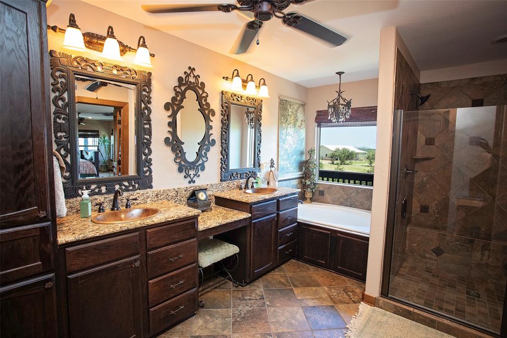 7060 Hells Gate Loop Strawn, TX 76475 - Photo 10 of 40 Ensuite bathroom featuring a shower stall, a garden tub, ceiling fan, and two vanities
