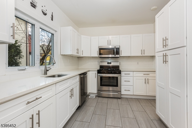 112 Pompton Avenue, Unit 1 Verona, NJ 07044 - Photo 14 of 25 a kitchen with white cabinets stainless steel appliances and a sink