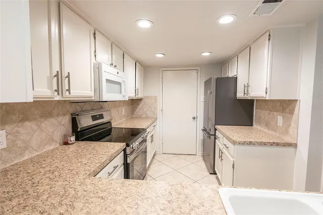 a kitchen with stainless steel appliances granite countertop a refrigerator a stove and a sink