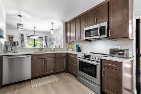 a kitchen with stainless steel appliances granite countertop grey cabinets a stove a sink and dishwasher