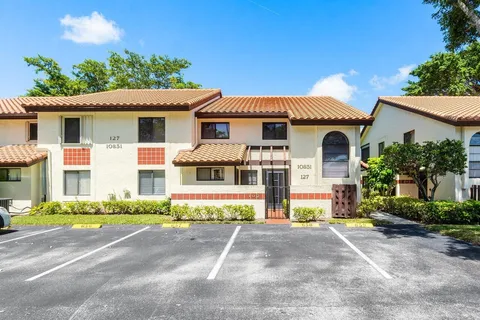 a view of a white house with large windows and a small yard