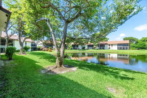a view of a house next to a lake with a large tree