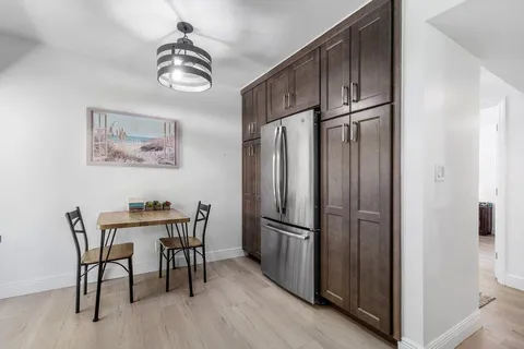 a kitchen with stainless steel appliances granite countertop a refrigerator and a wooden floor