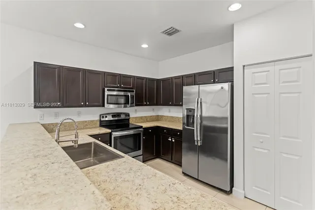 a kitchen with kitchen island granite countertop a sink stainless steel appliances and cabinets