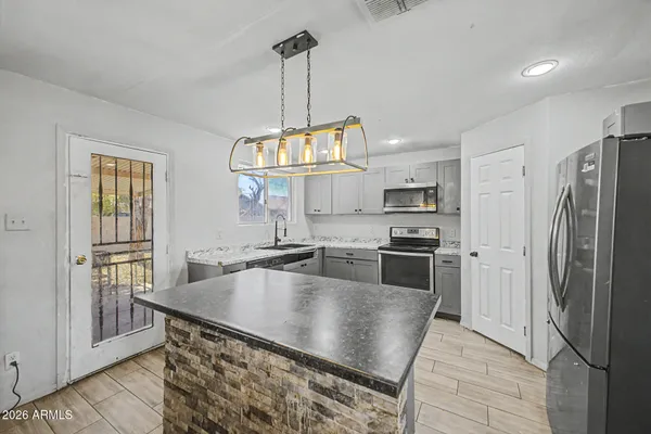 a kitchen with stainless steel appliances granite countertop a refrigerator a sink a stove and white cabinets