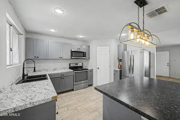 a kitchen with stainless steel appliances granite countertop a stove a sink a refrigerator and a granite counter tops
