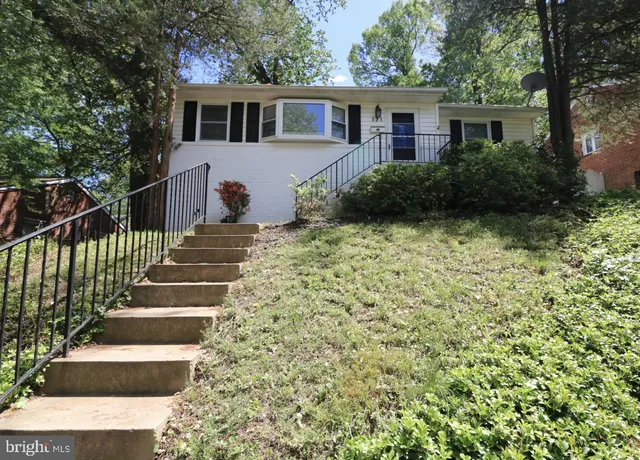 a view of a house with wooden fence next to a yard