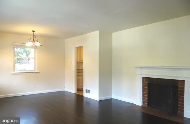 an empty room with wooden floor fireplace and windows
