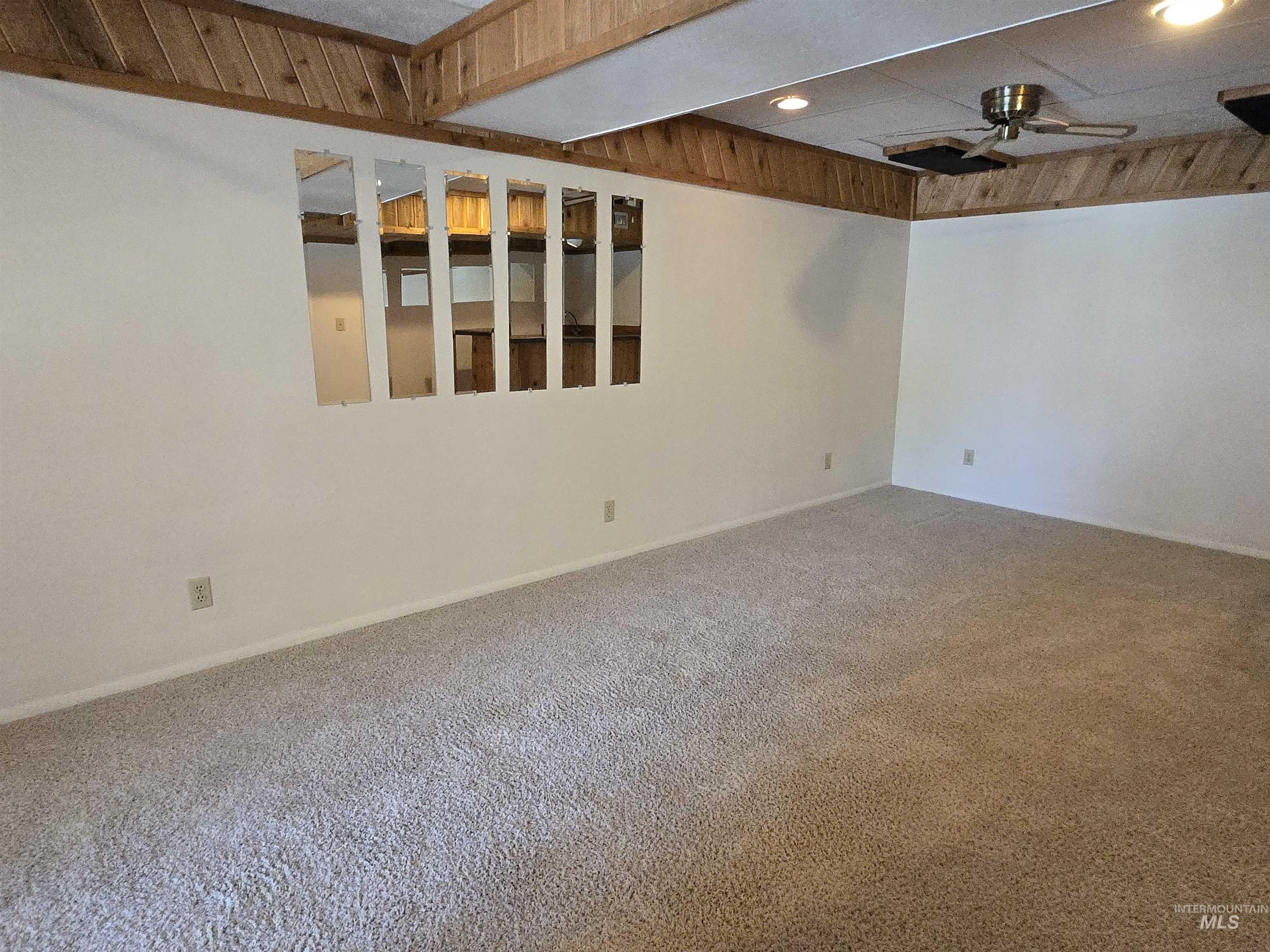 12050 West Hidden Valley Rim Road Boise, ID 83709 - Photo 18 of 39 Spacious room featuring light-colored carpeting, white painted walls, and a ceiling with wood-paneled accents and exposed beams