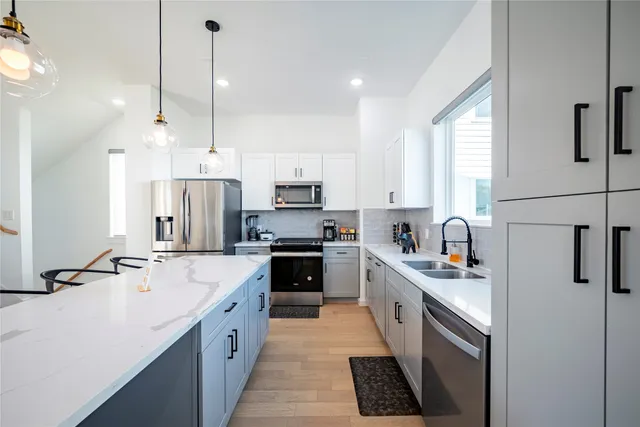 a kitchen with stainless steel appliances kitchen island a sink a stove a refrigerator and white cabinets