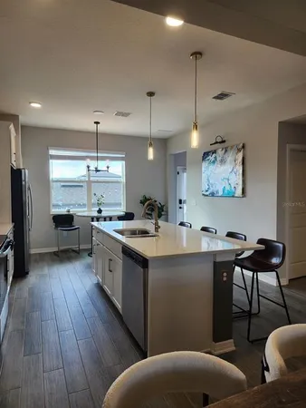 a kitchen with stainless steel appliances granite countertop a sink a stove and a wooden floors