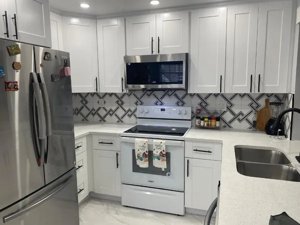 a kitchen with stainless steel appliances granite countertop a refrigerator a stove and a sink