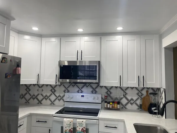 a view of a kitchen with kitchen island a sink stainless steel appliances and cabinets