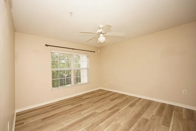 an empty room with a window and a ceiling fan